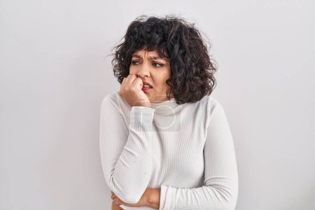 Photo for Hispanic woman with curly hair standing over isolated background looking stressed and nervous with hands on mouth biting nails. anxiety problem. - Royalty Free Image