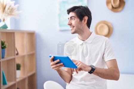 Photo for Young hispanic man smiling confident using touchpad at home - Royalty Free Image