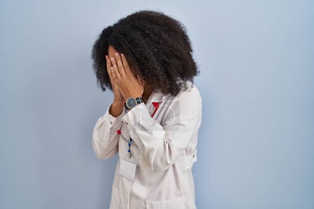 Photo for Young african american woman wearing doctor uniform and stethoscope with sad expression covering face with hands while crying. depression concept. - Royalty Free Image