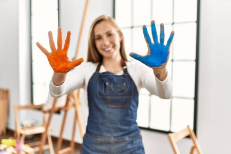 Photo for Young caucasian woman smiling confident showing painted palm hands at art studio - Royalty Free Image