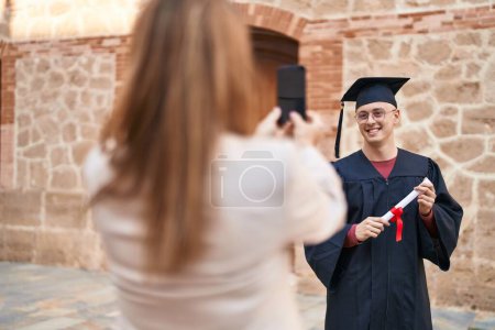 Photo for Man and woman mother and graduated son making photo by smartphone at university - Royalty Free Image