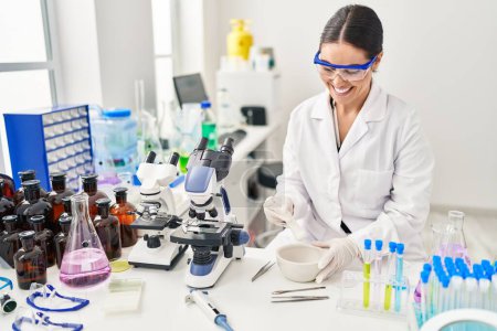 Photo for Young beautiful hispanic woman scientist smiling confident mixing sample at laboratory - Royalty Free Image