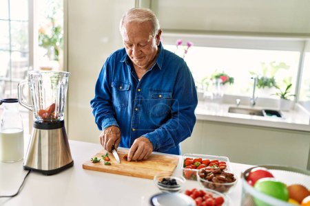 Foto de Hombre mayor sonriendo seguro de cortar datil en la cocina - Imagen libre de derechos