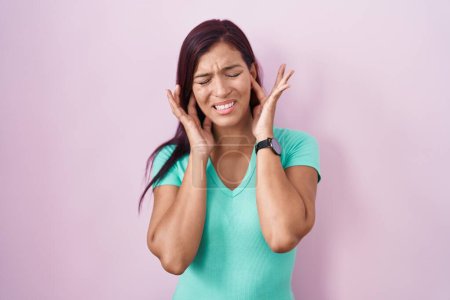 Photo for Young hispanic woman standing over pink background covering ears with fingers with annoyed expression for the noise of loud music. deaf concept. - Royalty Free Image