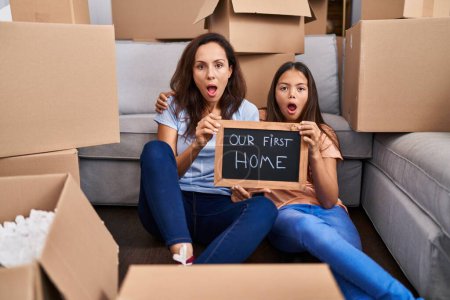 Photo for Young mother and daughter sitting on the floor at new home afraid and shocked with surprise and amazed expression, fear and excited face. - Royalty Free Image