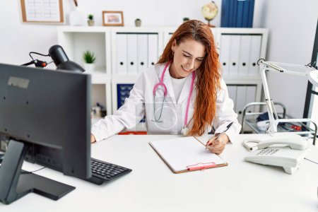 Téléchargez les photos : Jeune rousse femme portant l'uniforme de médecin travaillant à l'hôpital - en image libre de droit