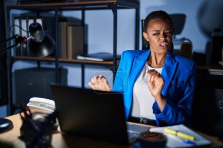Photo for Beautiful african american woman working at the office at night disgusted expression, displeased and fearful doing disgust face because aversion reaction. with hands raised - Royalty Free Image