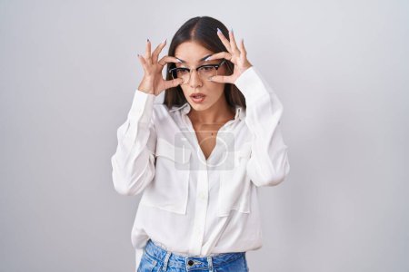 Photo for Young brunette woman wearing glasses trying to open eyes with fingers, sleepy and tired for morning fatigue - Royalty Free Image
