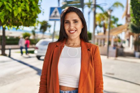 Téléchargez les photos : Jeune femme hispanique souriante marche confiante dans la rue - en image libre de droit