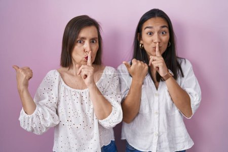 Téléchargez les photos : Mère et fille hispaniques demandant ensemble de se taire avec le doigt sur les lèvres pointant la main sur le côté. silence et concept secret. - en image libre de droit