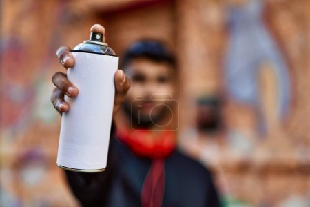 Téléchargez les photos : Jeune homme arabe détendu tenant un spray graffiti dans la rue - en image libre de droit