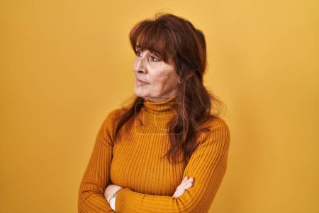 Téléchargez les photos : Middle age hispanic woman standing over yellow background looking to the side with arms crossed convinced and confident - en image libre de droit