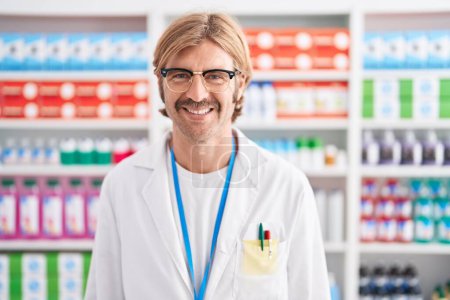 Foto de Caucasian man with mustache working at pharmacy drugstore with a happy and cool smile on face. lucky person. - Imagen libre de derechos