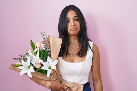 Foto de Mujer morena sosteniendo ramo de flores blancas deprimidas y preocupadas por la angustia, llorando enojado y asustado. expresión triste. - Imagen libre de derechos