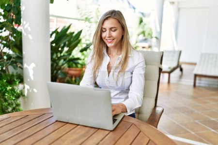 Photo for Young blonde woman smiling happy using laptop working at the terrace. - Royalty Free Image