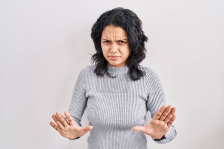 Photo for Hispanic woman with dark hair standing over isolated background moving away hands palms showing refusal and denial with afraid and disgusting expression. stop and forbidden. - Royalty Free Image