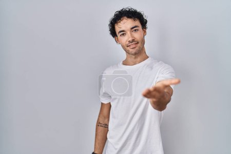 Téléchargez les photos : Homme hispanique debout sur fond isolé souriant gai offrant la main de la paume donnant assistance et acceptation. - en image libre de droit