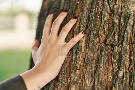Photo for Young beautiful hispanic woman touching tree with hand at park - Royalty Free Image