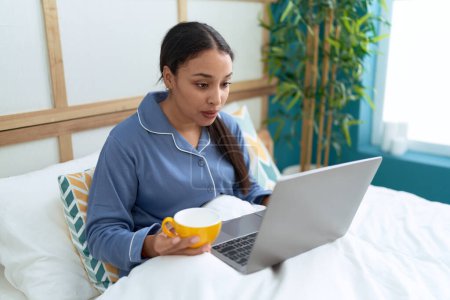 Photo for Young arab woman using laptop drinking coffee at bedroom - Royalty Free Image