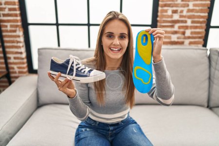 Photo for Young woman holding shoe insole smiling and laughing hard out loud because funny crazy joke. - Royalty Free Image