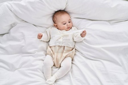 Foto de Adorable bebé relajado acostado en la cama en el dormitorio - Imagen libre de derechos