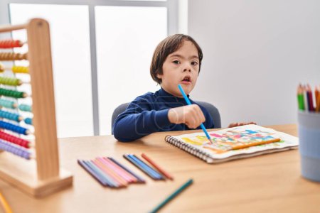 Foto de Síndrome de Down niño dibujo en el cuaderno en la escuela - Imagen libre de derechos