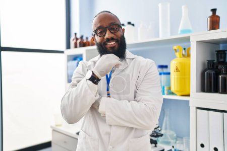 Photo for Young african american man wearing scientist uniform standing at laboratory - Royalty Free Image