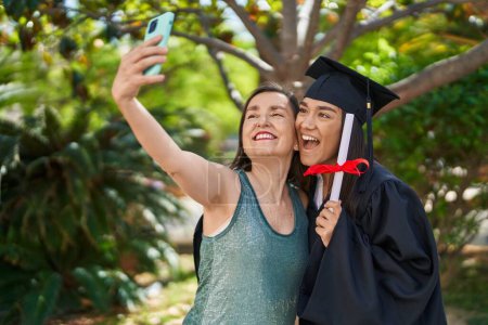 Photo for Two women mother and graduated daughter make selfie by smartphone at park - Royalty Free Image