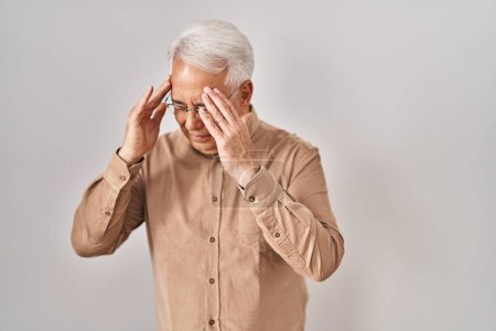 Foto de Hombre mayor hispano usando gafas con la mano en la cabeza para el dolor en la cabeza porque el estrés. padecer migraña. - Imagen libre de derechos