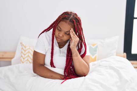 Foto de Mujer afroamericana estresada sentada en la cama en el dormitorio - Imagen libre de derechos