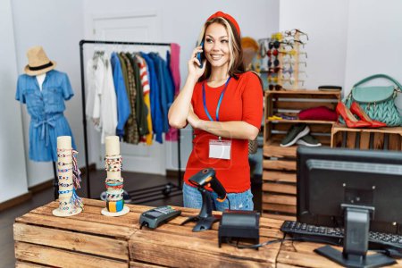 Photo for Young caucasian shopkeeper woman smiling happy talking on the smartphone working at clothing store. - Royalty Free Image