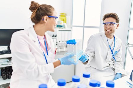 Téléchargez les photos : Man and woman wearing scientist uniform holding test tube at laboratory - en image libre de droit