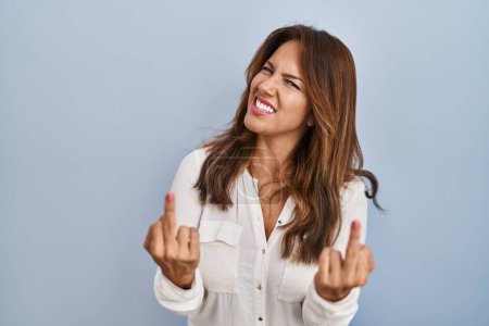 Foto de Hispanic woman standing over isolated background showing middle finger doing fuck you bad expression, provocation and rude attitude. screaming excited - Imagen libre de derechos