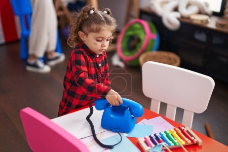 Photo for Adorable caucasian girl playing with telephone toy standing at kindergarten - Royalty Free Image