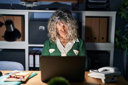Foto de Middle age woman working at night using computer laptop skeptic and nervous, frowning upset because of problem. negative person. - Imagen libre de derechos