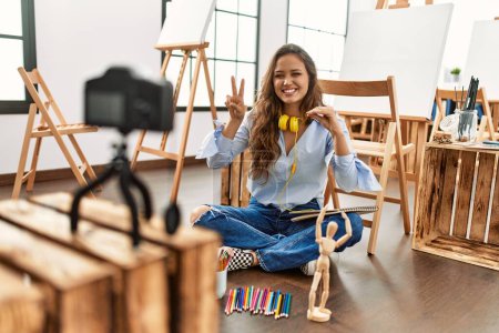 Téléchargez les photos : Jeune belle artiste hispanique enregistrement dessin leçon communiquer avec le langage sourd au studio d'art - en image libre de droit