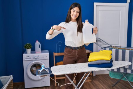 Photo for Young brunette woman with folded laundry after ironing pointing finger to one self smiling happy and proud - Royalty Free Image