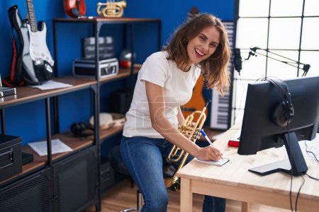 Foto de Joven mujer músico sosteniendo trompeta componiendo canción en el estudio de música - Imagen libre de derechos