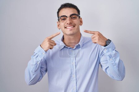 Photo for Handsome hispanic man wearing business clothes and glasses smiling cheerful showing and pointing with fingers teeth and mouth. dental health concept. - Royalty Free Image