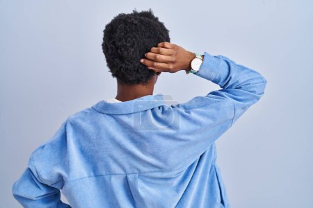 Photo for African american woman standing over blue background backwards thinking about doubt with hand on head - Royalty Free Image