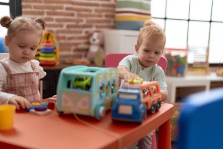 Téléchargez les photos : Adorable fille et garçon jouant avec des jouets sur la table à la maternelle - en image libre de droit