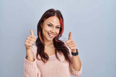 Photo for Young caucasian woman wearing pink sweater over isolated background approving doing positive gesture with hand, thumbs up smiling and happy for success. winner gesture. - Royalty Free Image