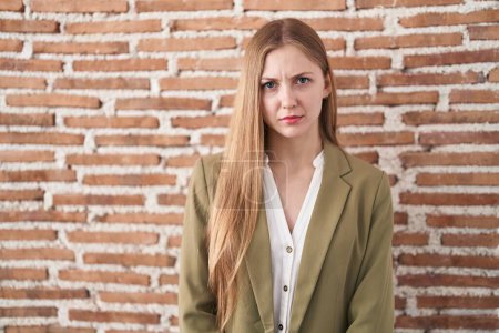 Photo for Young caucasian woman standing over bricks wall background skeptic and nervous, frowning upset because of problem. negative person. - Royalty Free Image