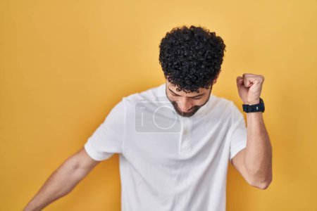 Photo for Arab man standing over yellow background dancing happy and cheerful, smiling moving casual and confident listening to music - Royalty Free Image