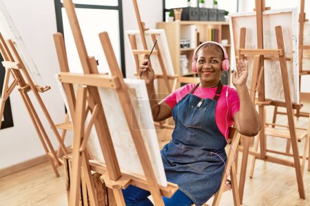 Téléchargez les photos : Femme afro-américaine senior à l'écoute de dessins musicaux au studio d'art - en image libre de droit