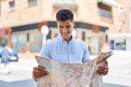 Foto de Young hispanic man smiling confident holding city map at street - Imagen libre de derechos