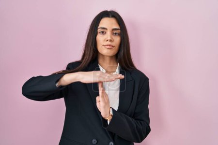 Foto de Young brunette woman wearing business style over pink background doing time out gesture with hands, frustrated and serious face - Imagen libre de derechos