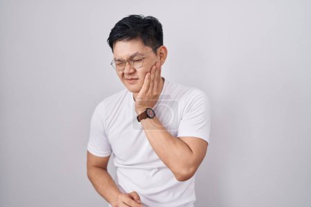 Photo for Young asian man standing over white background touching mouth with hand with painful expression because of toothache or dental illness on teeth. dentist - Royalty Free Image