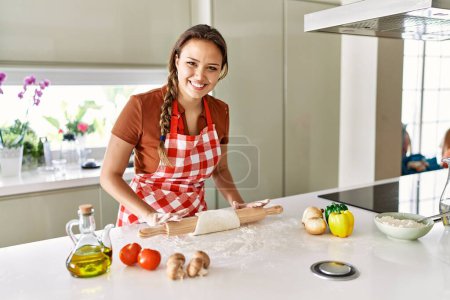 Photo for Young beautiful hispanic woman smiling confident kneading dough pizza at the kitchen - Royalty Free Image