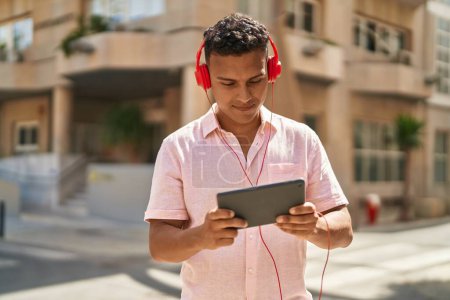 Téléchargez les photos : Jeune latin homme souriant confiant jouer jeu vidéo à la rue - en image libre de droit